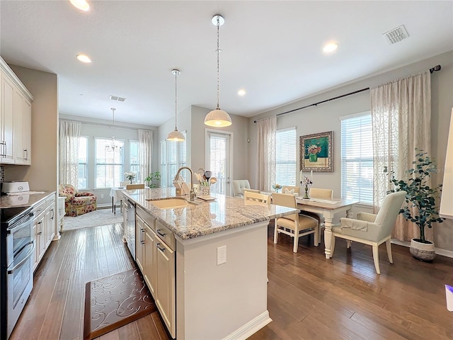 kitchen featuring appliances with stainless steel finishes, sink, pendant lighting, a center island with sink, and white cabinetry