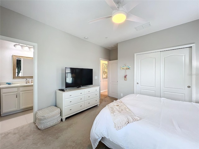 bedroom with ceiling fan, sink, ensuite bathroom, light colored carpet, and a closet