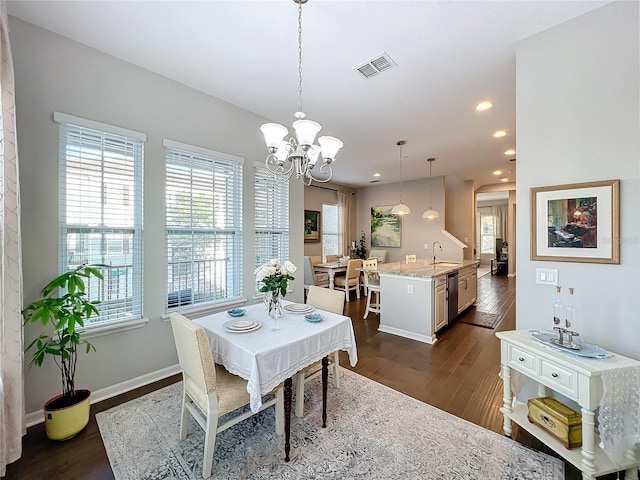 dining area with dark hardwood / wood-style floors, an inviting chandelier, and sink