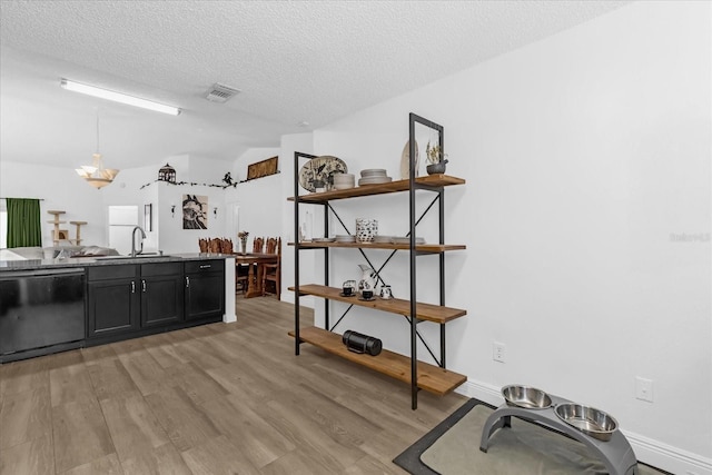 kitchen featuring a textured ceiling, sink, pendant lighting, dishwasher, and light hardwood / wood-style floors