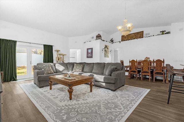 living room with french doors, hardwood / wood-style flooring, vaulted ceiling, and a notable chandelier