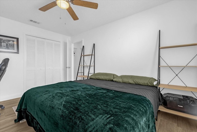 bedroom with ceiling fan, a closet, and wood-type flooring