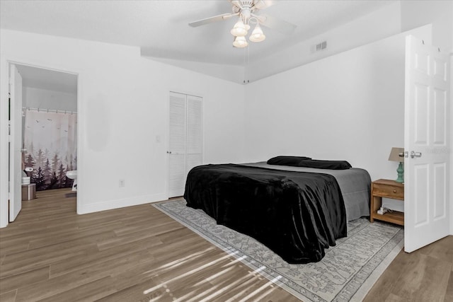 bedroom with ceiling fan, wood-type flooring, ensuite bathroom, and lofted ceiling