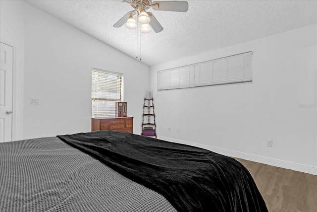 bedroom featuring a textured ceiling, ceiling fan, wood-type flooring, and vaulted ceiling