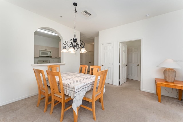 dining space with light carpet and a notable chandelier