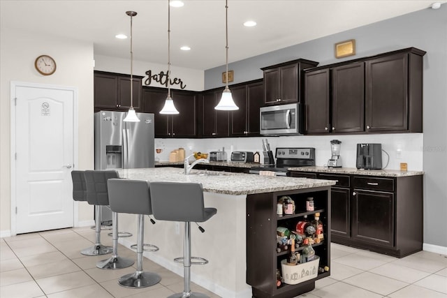 kitchen featuring appliances with stainless steel finishes, dark brown cabinetry, a kitchen island with sink, and pendant lighting