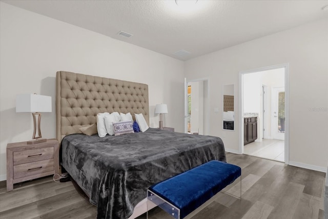 bedroom featuring wood-type flooring, a textured ceiling, and connected bathroom