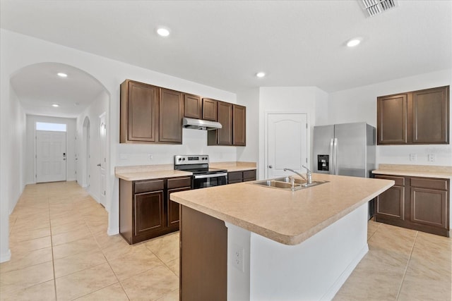 kitchen featuring a kitchen island with sink, sink, light tile patterned floors, dark brown cabinetry, and stainless steel appliances