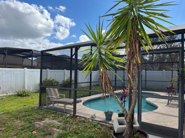 view of pool with glass enclosure, a patio area, and a yard