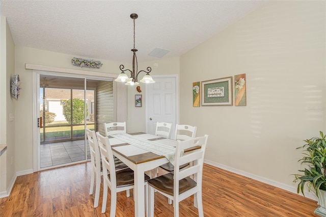 dining room featuring a textured ceiling, light hardwood / wood-style floors, and a chandelier