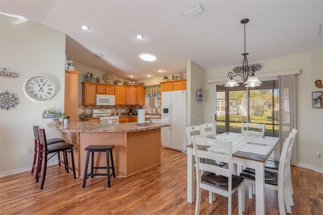 kitchen featuring white appliances, lofted ceiling, decorative backsplash, kitchen peninsula, and light hardwood / wood-style flooring