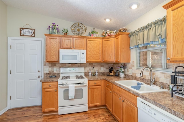 kitchen featuring white appliances, a textured ceiling, tasteful backsplash, sink, and light hardwood / wood-style flooring