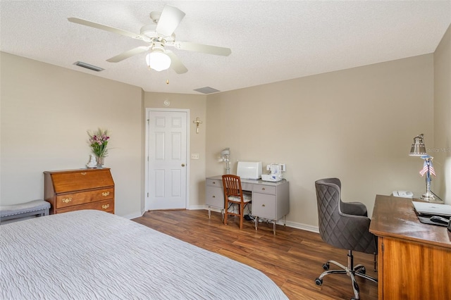 bedroom with a textured ceiling, ceiling fan, and dark hardwood / wood-style flooring