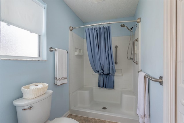 bathroom featuring a textured ceiling, toilet, and a shower with shower curtain