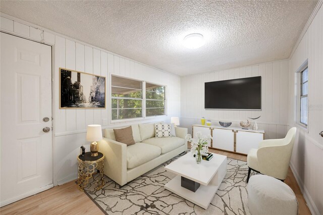 living room with wood walls, light wood-type flooring, and a textured ceiling