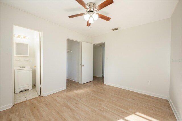 unfurnished bedroom with light hardwood / wood-style flooring, ensuite bath, and ceiling fan