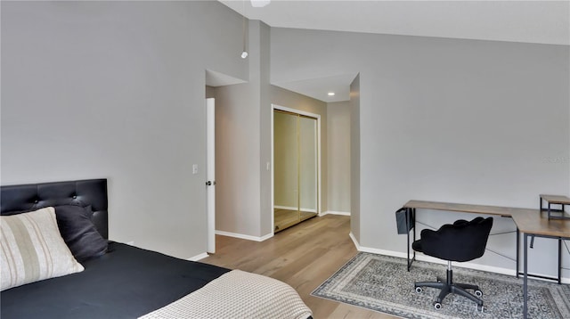 bedroom with a closet, high vaulted ceiling, and light hardwood / wood-style floors