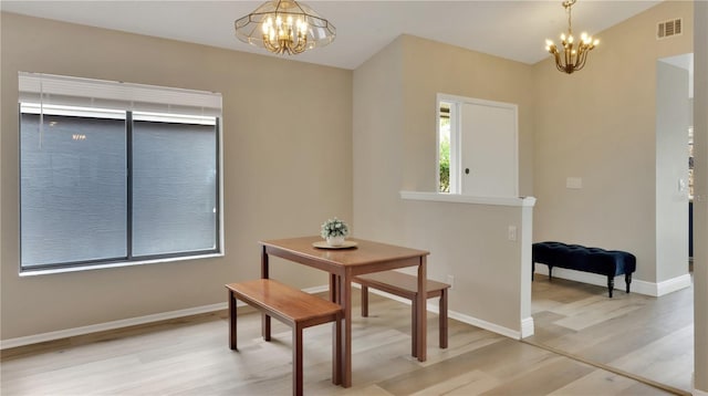 dining space featuring wood-type flooring, an inviting chandelier, and a healthy amount of sunlight