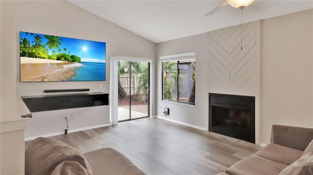 living room featuring ceiling fan, a fireplace, vaulted ceiling, and light wood-type flooring