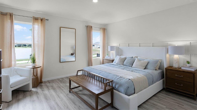 bedroom with light hardwood / wood-style flooring and a water view