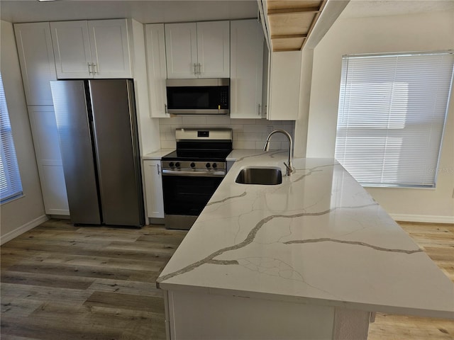 kitchen with white cabinetry, light stone countertops, sink, and appliances with stainless steel finishes