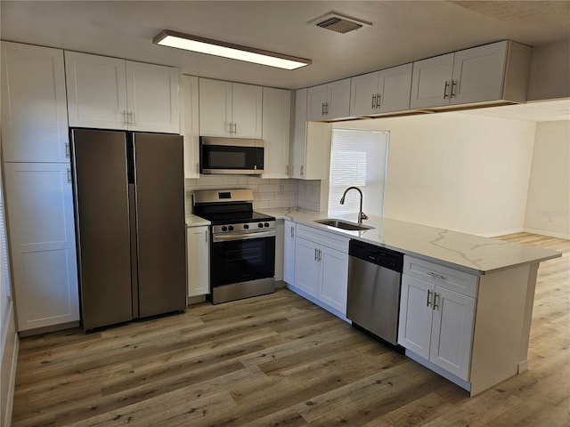 kitchen featuring white cabinets, stainless steel appliances, light hardwood / wood-style floors, and sink