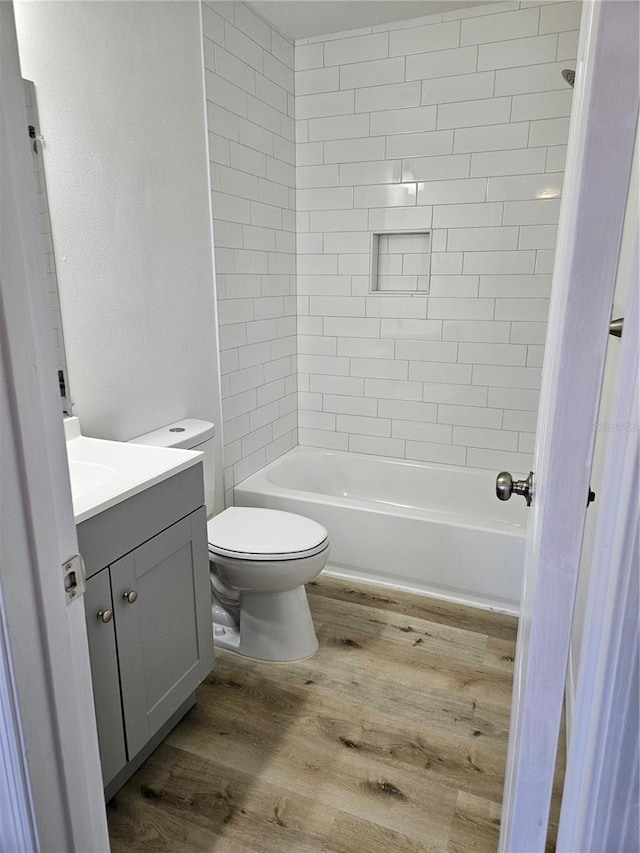 full bathroom with hardwood / wood-style floors, vanity, toilet, and tiled shower / bath combo