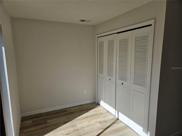 unfurnished bedroom with hardwood / wood-style floors, a textured ceiling, and a closet