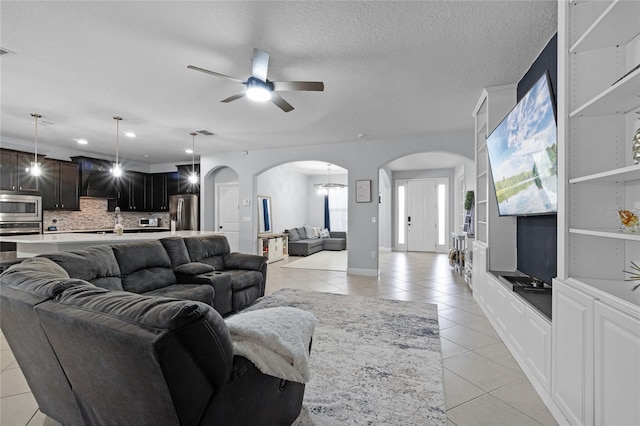 living room featuring built in shelves, ceiling fan, sink, a textured ceiling, and light tile patterned floors