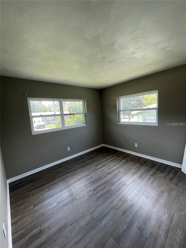 unfurnished room with dark wood-type flooring