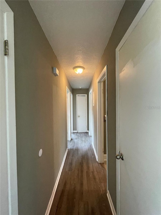 hall with dark hardwood / wood-style flooring and a textured ceiling