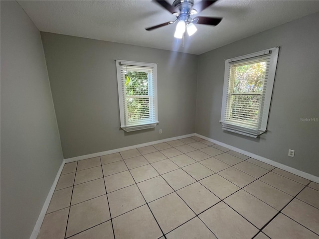 tiled spare room featuring ceiling fan, a textured ceiling, and a wealth of natural light