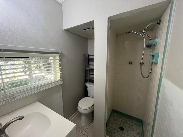 bathroom featuring tiled shower, tile patterned floors, toilet, and sink