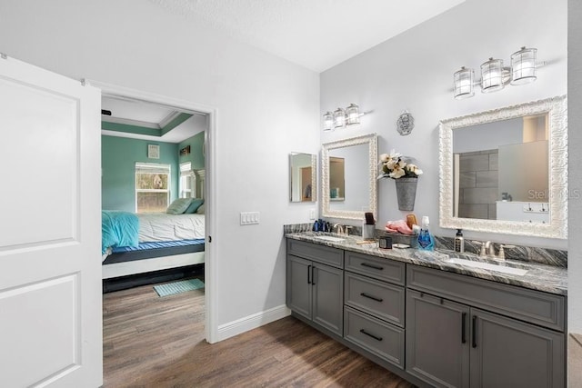 bathroom with baseboards, a sink, ensuite bath, and wood finished floors