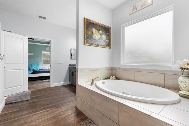 bathroom featuring visible vents, connected bathroom, vanity, wood finished floors, and a bath