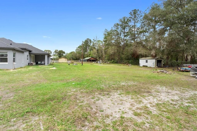 view of yard with a storage shed, an outbuilding, and fence