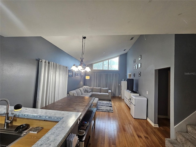 kitchen with hardwood / wood-style floors, high vaulted ceiling, decorative light fixtures, and an inviting chandelier