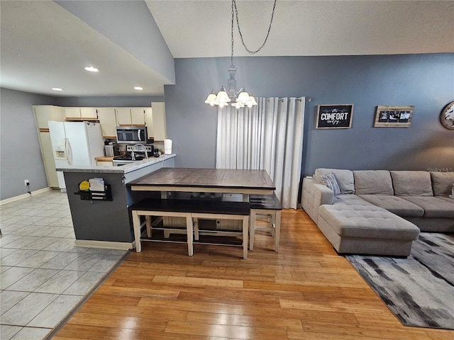 kitchen with pendant lighting, an inviting chandelier, light wood-type flooring, kitchen peninsula, and stainless steel appliances