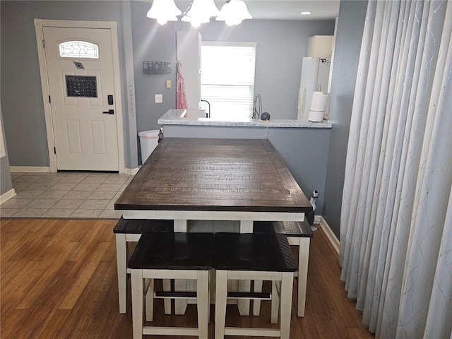 kitchen featuring tile patterned floors, kitchen peninsula, white fridge, a chandelier, and a breakfast bar