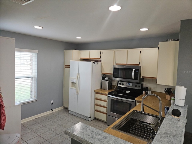 kitchen with sink, light tile patterned floors, cream cabinetry, and appliances with stainless steel finishes