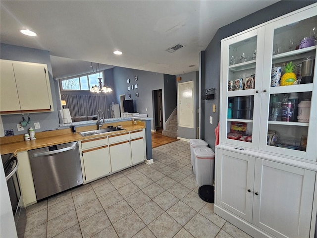 kitchen featuring pendant lighting, sink, stainless steel dishwasher, light tile patterned flooring, and white cabinetry