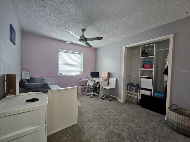 home office featuring a textured ceiling, dark carpet, and ceiling fan