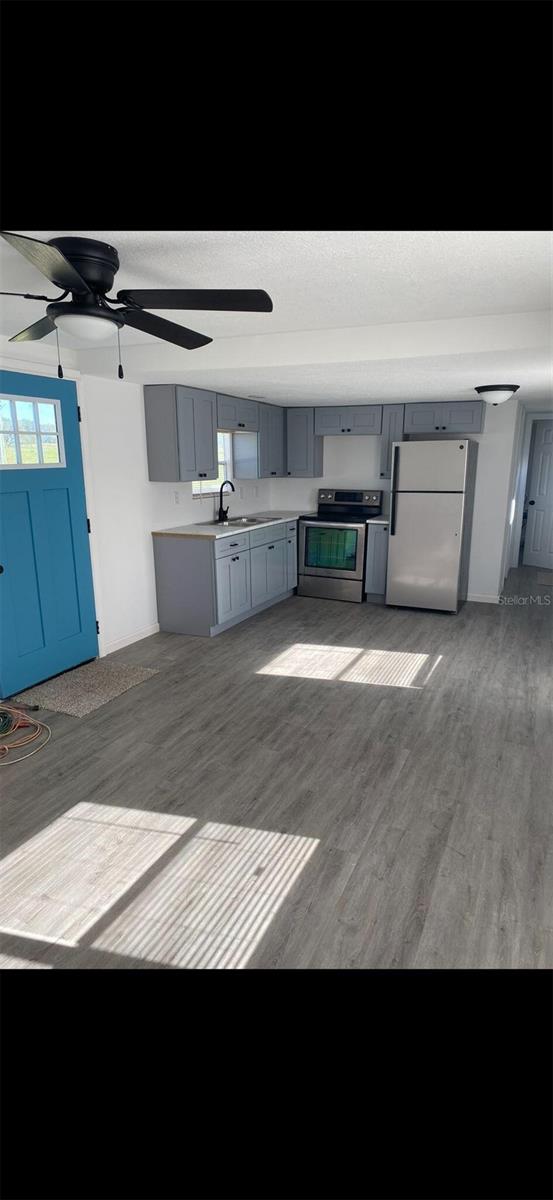 kitchen featuring dark wood-type flooring, sink, gray cabinets, stainless steel electric range oven, and fridge