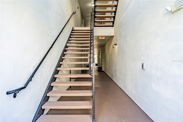 stairs with concrete floors and a high ceiling