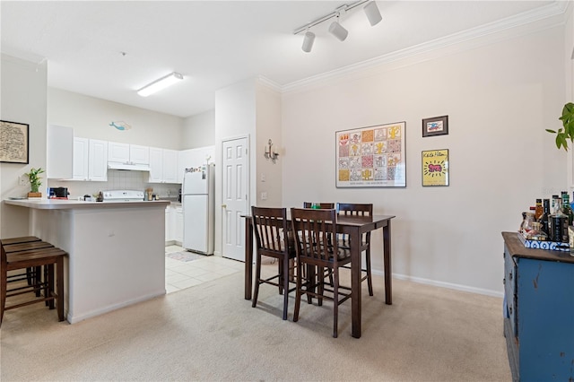 dining area featuring crown molding, track lighting, and light carpet