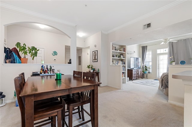 carpeted dining area featuring crown molding and built in shelves