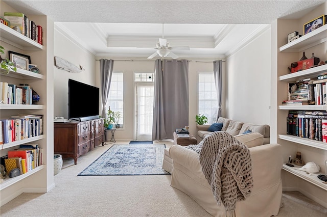 living room featuring a raised ceiling, light colored carpet, a textured ceiling, and built in shelves