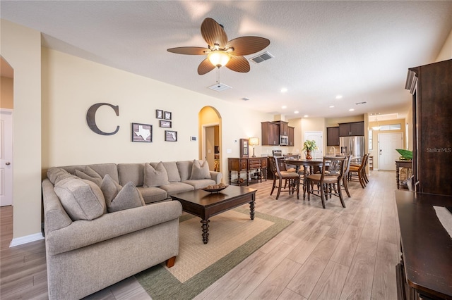 living room with ceiling fan, light hardwood / wood-style floors, and a textured ceiling