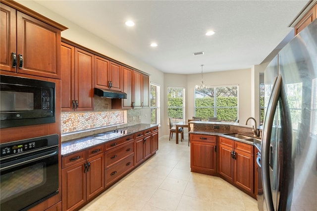 kitchen with dark stone counters, an inviting chandelier, black appliances, sink, and decorative light fixtures