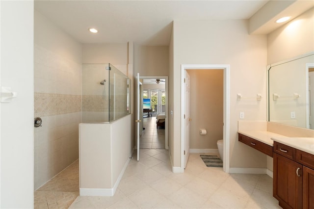 bathroom featuring ceiling fan, toilet, tiled shower, and vanity